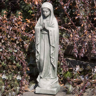 Campania International 14 inch Madonna Statue placed in the garden. Religious garden statues, made of cast stone in a range of color options.