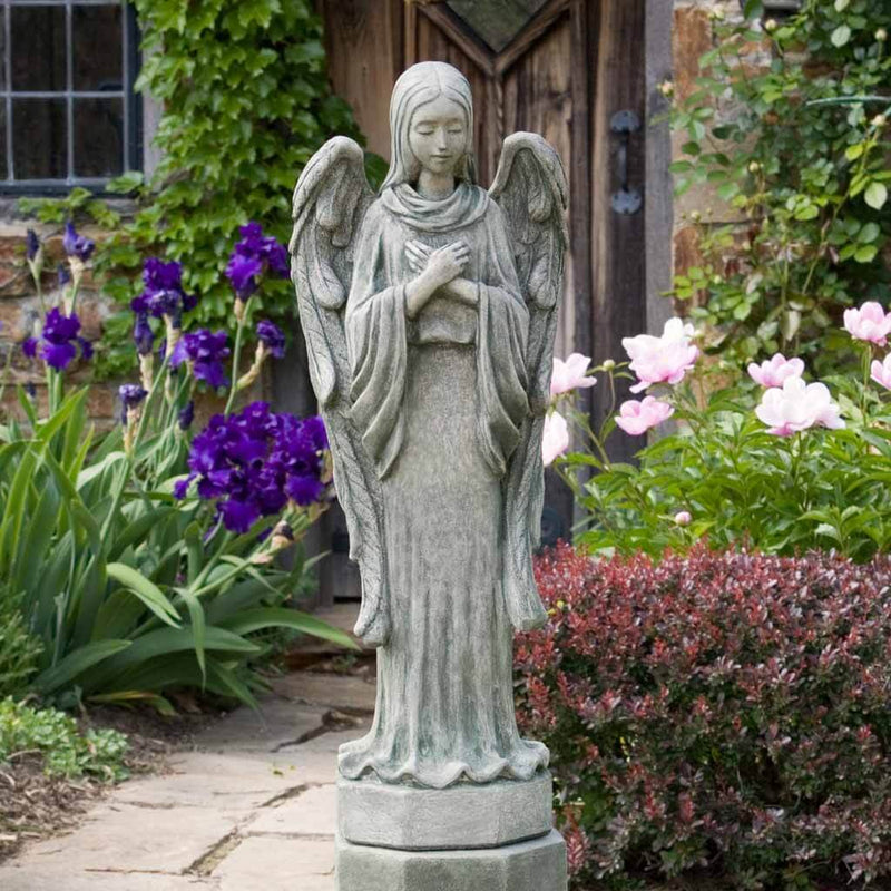 Campania International Autumn Angel Statue placed in the garden. Religious garden statues, made of cast stone in a range of color options.