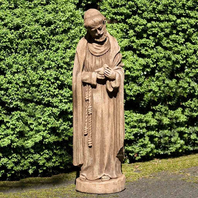 Campania International St. Francis with Baby Bird Statue placed in the garden. Religious garden statues, made of cast stone in a range of color options.