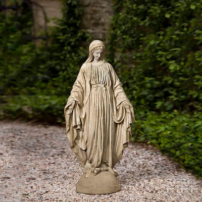 Campania International Classic Madonna Statue placed in the garden. Religious garden statues, made of cast stone in a range of color options.