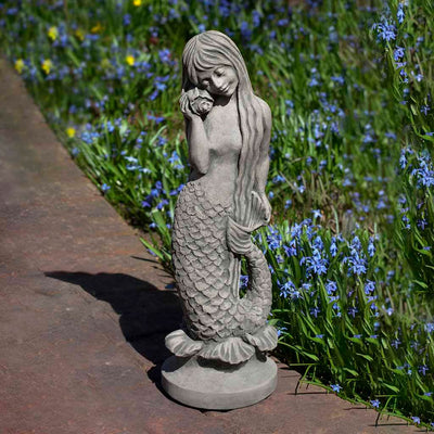 Campania International Standing Mermaid Statue, set in the garden to add charm and character. The statue is shown in the Alpine Stone Patina.