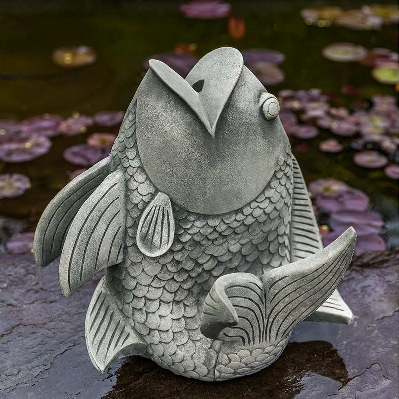 Campania International Sakana Planter, this fish planter is placed by a pond and shown in the Alpine Stone Patina.